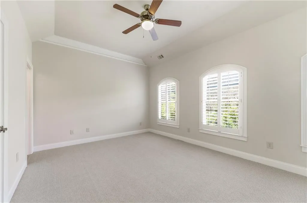 Spare room with light colored carpet, ceiling fan, and vaulted ceiling