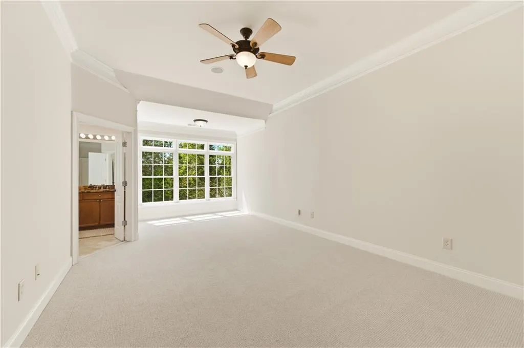 Spare room with light colored carpet, ornamental molding, and a ceiling fan
