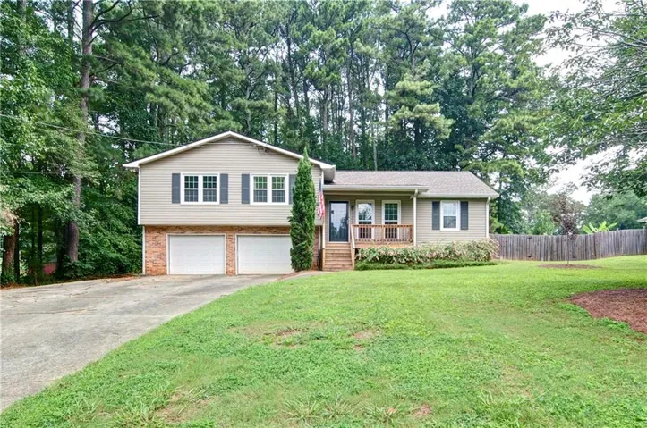 Split-level residence featuring a light-colored siding exterior, an attached garage, and a front porch with natural wood railings plus an EXTRA 2 car-garage Workshop in the back.