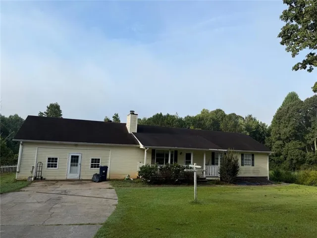 Single-story residence with light-colored siding, a dark shingle roof, and an attached garage