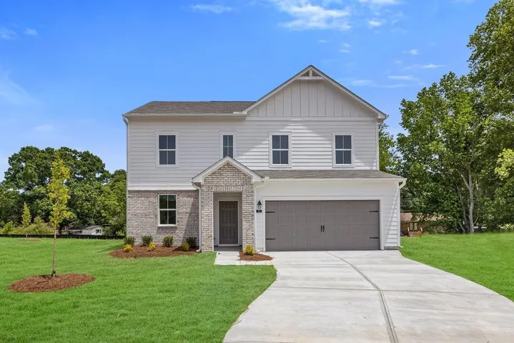 Two-story residence featuring light-colored siding, a prominent gable, and a two-car garage with a gray door