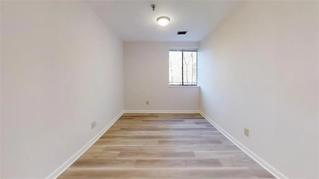 Empty room with visible vents, light wood-style flooring, and baseboards
