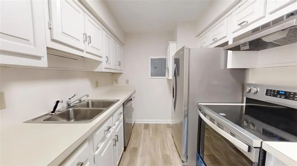 Kitchen featuring appliances with stainless steel finishes, white cabinets, electric panel, and a sink