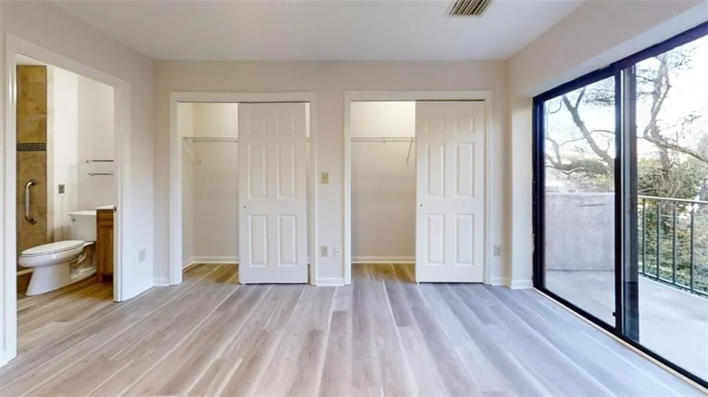 Unfurnished bedroom featuring light wood-style floors, access to outside, visible vents, and baseboards