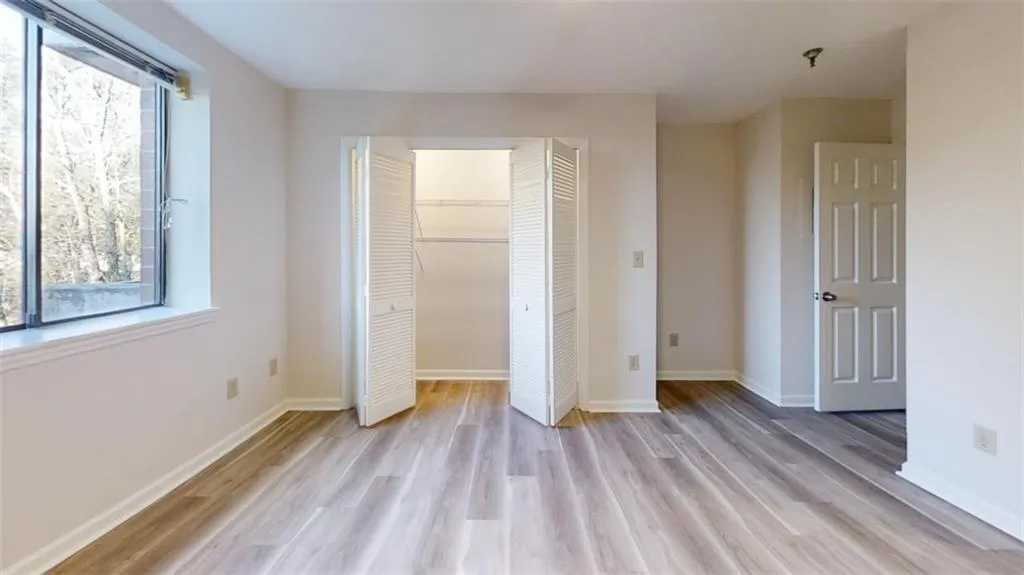 Unfurnished bedroom featuring a closet, light wood-style flooring, and baseboards