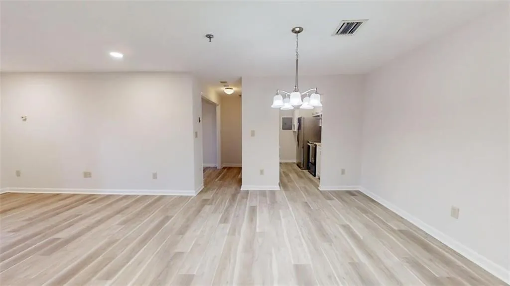 Empty room with light wood-type flooring, baseboards, visible vents, and recessed lighting