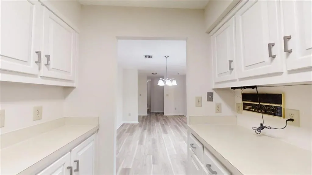Kitchen featuring a notable chandelier, visible vents, white cabinetry, light countertops, and light wood finished floors