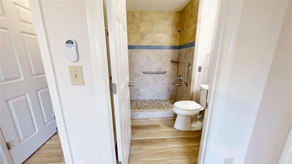 Bathroom featuring toilet, a shower stall, and wood finished floors