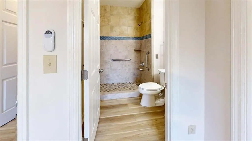 Bathroom with toilet, a stall shower, and wood finished floors