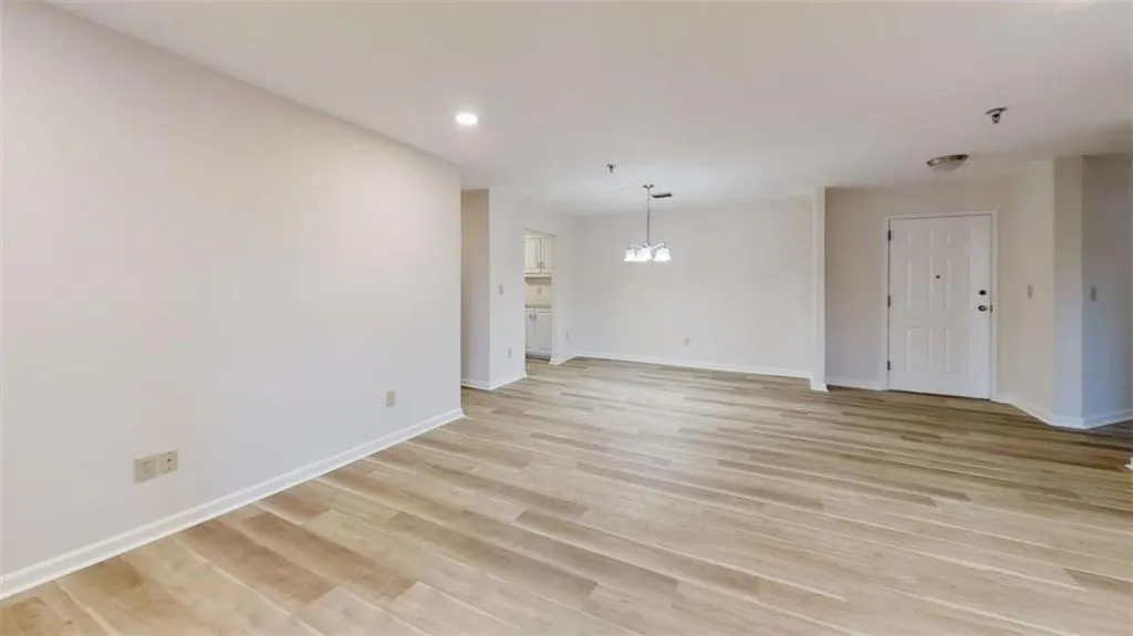 Unfurnished living room featuring light wood-type flooring, a notable chandelier, baseboards, and recessed lighting
