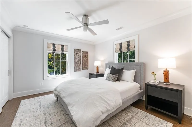 Bedroom with crown molding, wood finished floors, multiple windows, a ceiling fan, and a closet