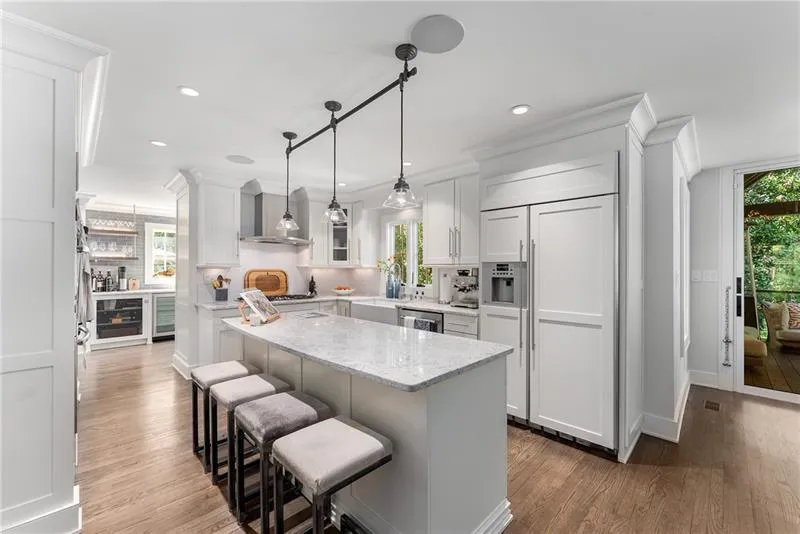 Kitchen featuring Carrera countertops, paneled fridge, glass insert cabinets, dark wood-type flooring, and a kitchen breakfast bar