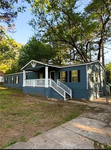 Exterior featuring blue siding, white porch railings, black window shutters, and a concrete driveway