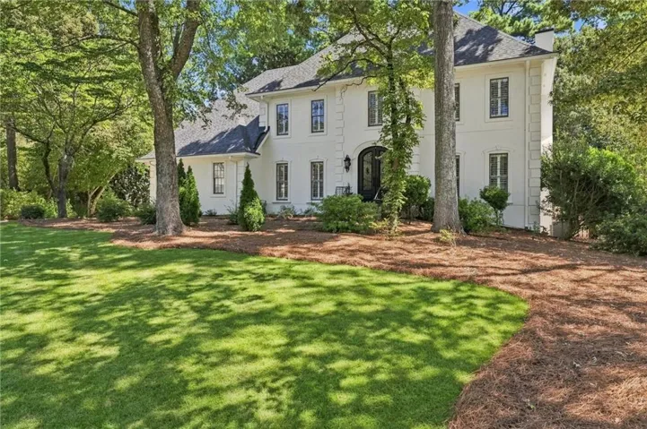 Stately white stucco exterior with dark trim windows, arched entry, and a dark shingle roof