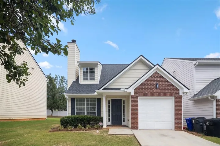 Exterior featuring brick and siding, a single-car garage, and a peaked roofline with a dormer