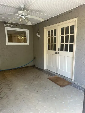 Property entrance with ceiling fan and stucco siding