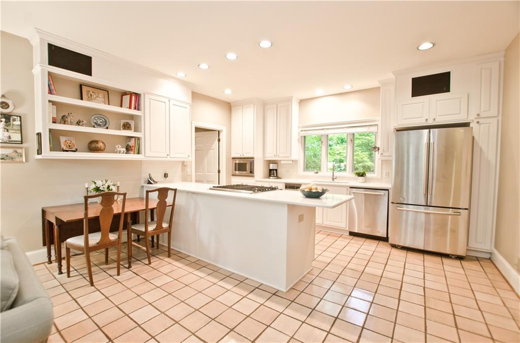 The kitchen has white cabinets, stainless appliances/ stone counters and gas cooktop