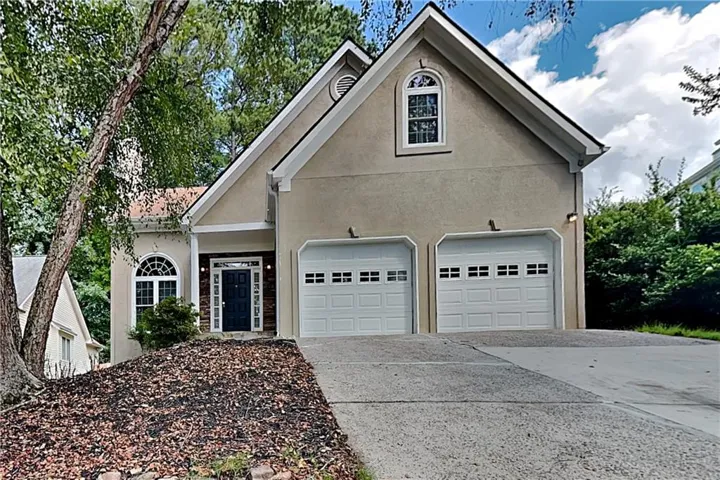 Stucco exterior, two-car garage, arched window, dark entry door, concrete driveway