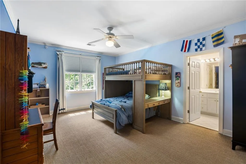 Carpeted room with a ceiling fan, crown molding, and a built-in bunk bed with an integrated desk