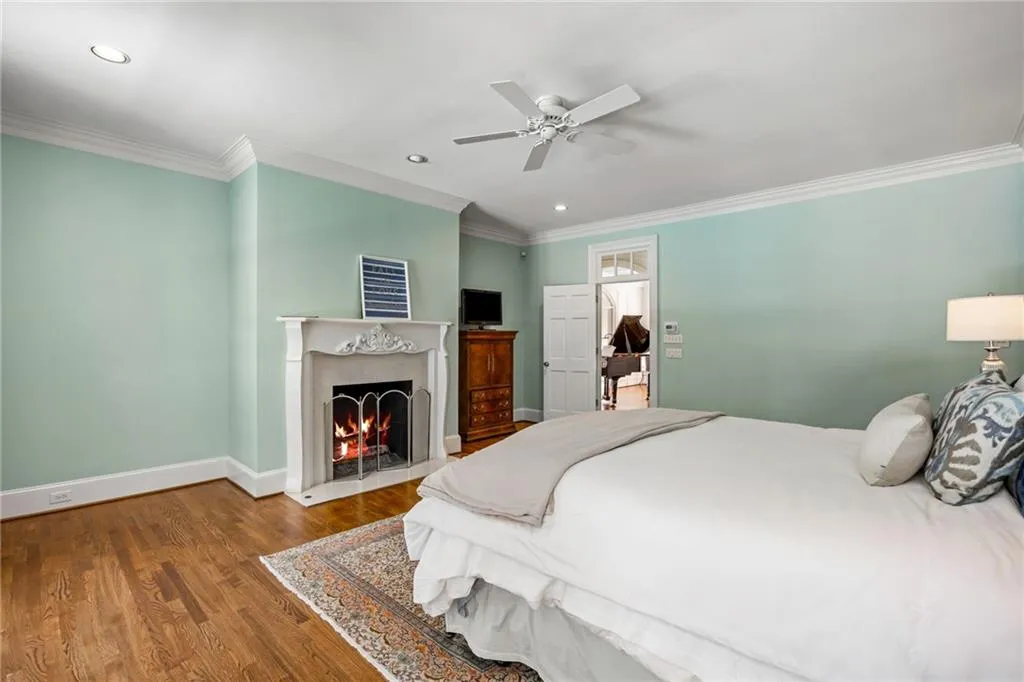 Hardwood flooring, crown molding, a decorative fireplace, recessed lighting, and a ceiling fan
