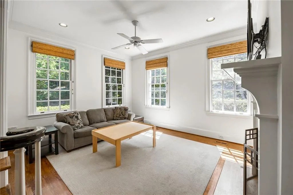 Hardwood flooring, recessed lighting, ceiling fan, white wall paint, and a fireplace with a white mantel