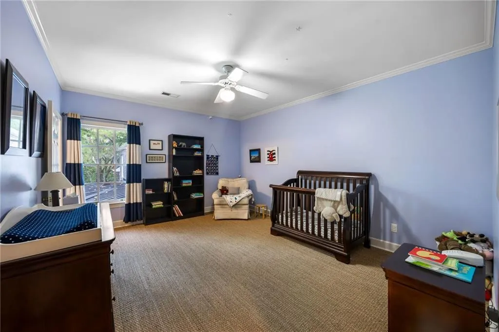 Room featuring crown molding, neutral tone carpet, and a ceiling fan