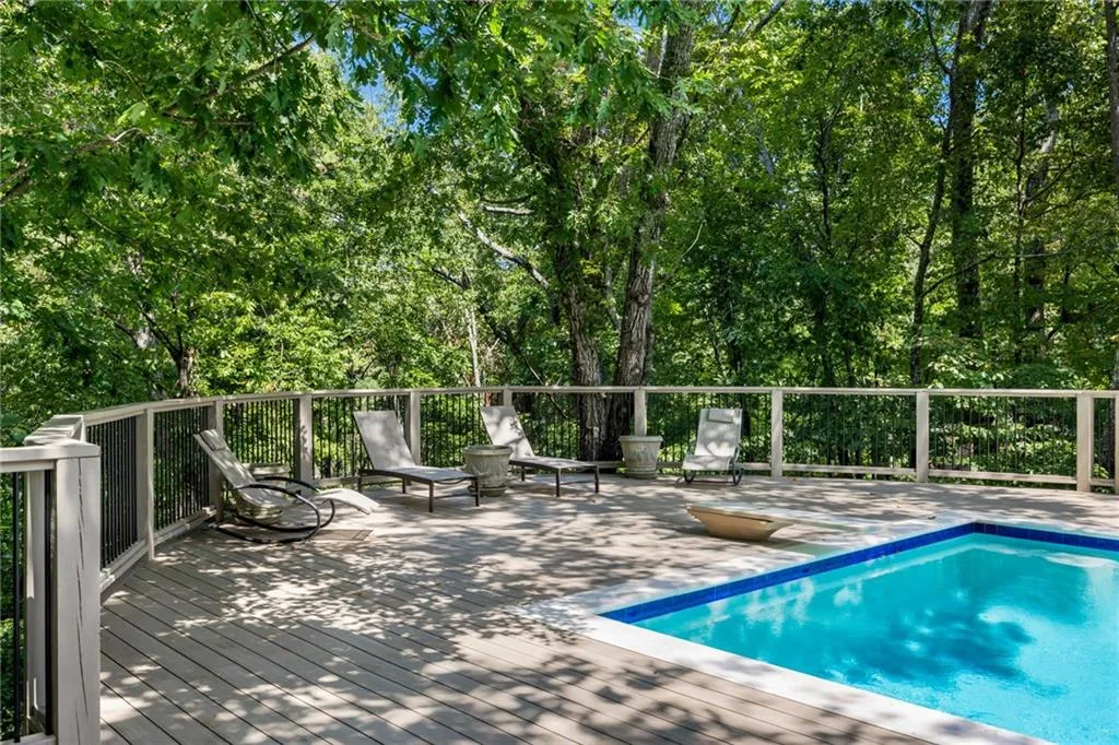 Expansive outdoor deck featuring wood-finish decking, a secure railing with black balusters, and an integrated swimming pool with blue tile accents