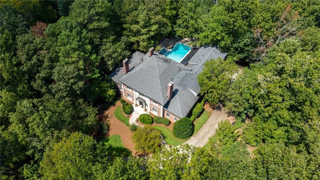 Brick exterior with multiple chimneys, a gabled roof, and an in-ground swimming pool