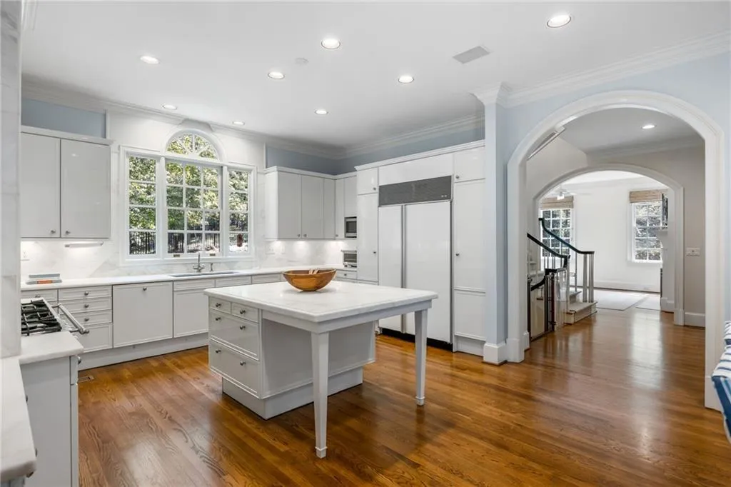 Kitchen featuring white cabinetry, wood-finish flooring, a central island, recessed lighting, and an arched window