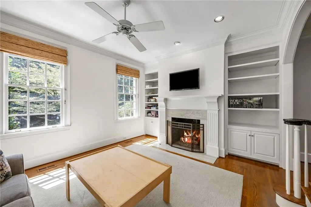 Fireplace with an ornate mantel, built-in shelving, hardwood flooring, and crown molding