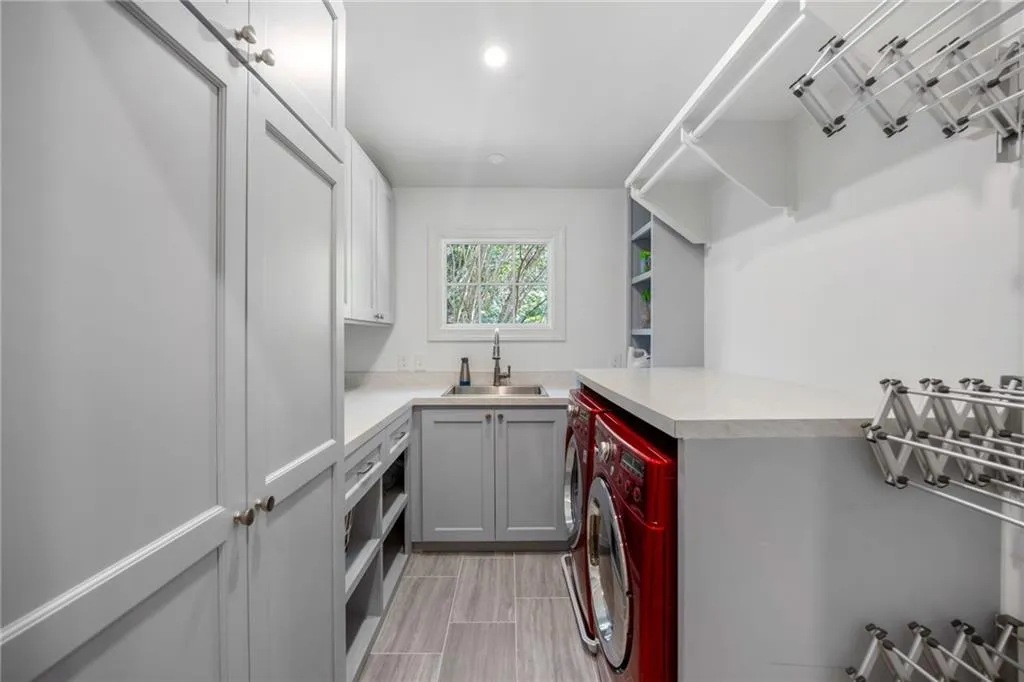 Laundry room with extensive gray cabinetry, light countertops, integrated sink, and wood-finish tile flooring