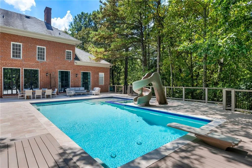 Resort-style saltwater pool with sun-shelf lounging area, surrounded by composite decking and cable-rail fencing