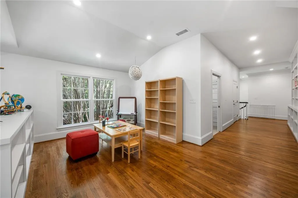 Hardwood flooring throughout, built-in shelving, vaulted ceiling, recessed lighting, and a large window