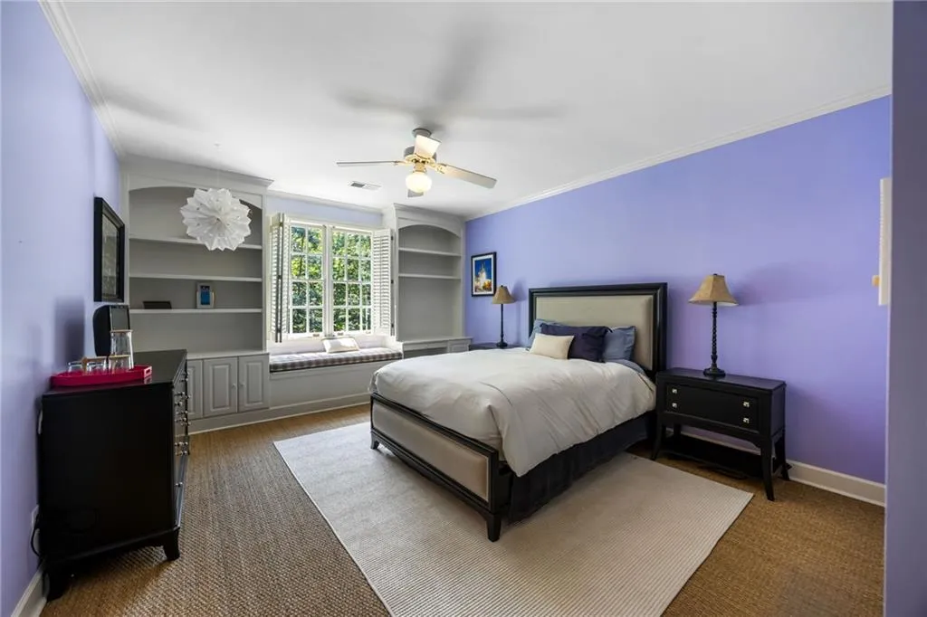 Window-framed built-in shelving, integrated window seat, ceiling fan, and crown molding