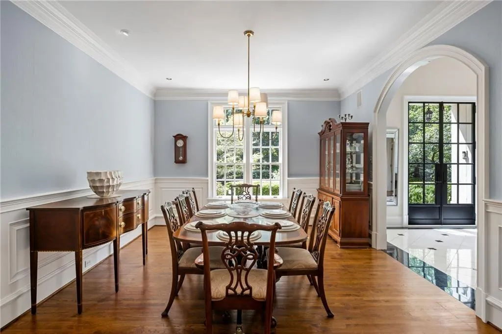 Hardwood flooring, arched doorway, picture frame wainscoting, crown molding, and a chandelier lighting fixture