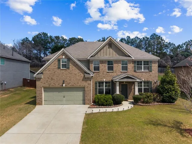 Brick and siding exterior featuring a two-car garage, established landscaping, a front porch with columns, and a concrete driveway