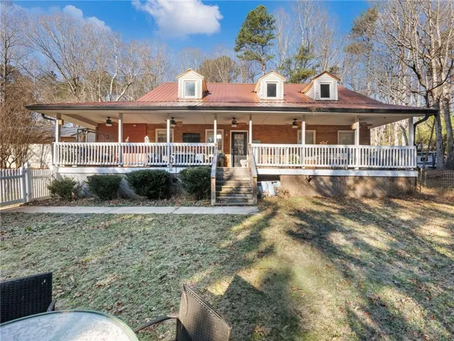 Farmhouse inspired home featuring covered porch, ceiling fan, and a metal roof