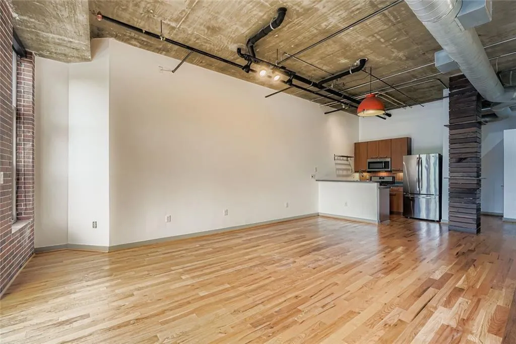 Unfurnished living room with light wood finished floors, a towering ceiling, and rail lighting