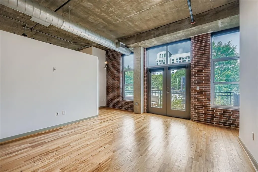 Empty room with brick wall, wood finished floors, and french doors