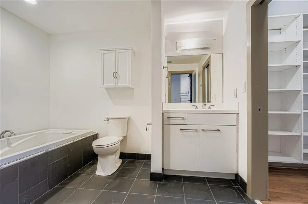 Full bath with vanity, a bath, dark tile patterned floors, and a closet
