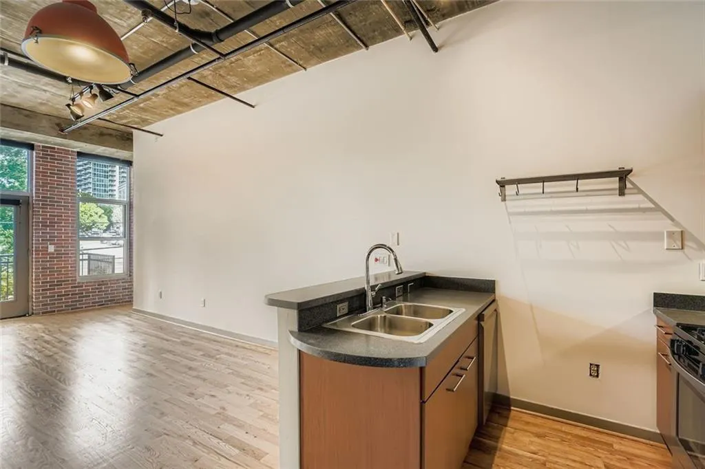 Kitchen featuring dark countertops, a peninsula, light wood-type flooring, brown cabinets, and brick wall