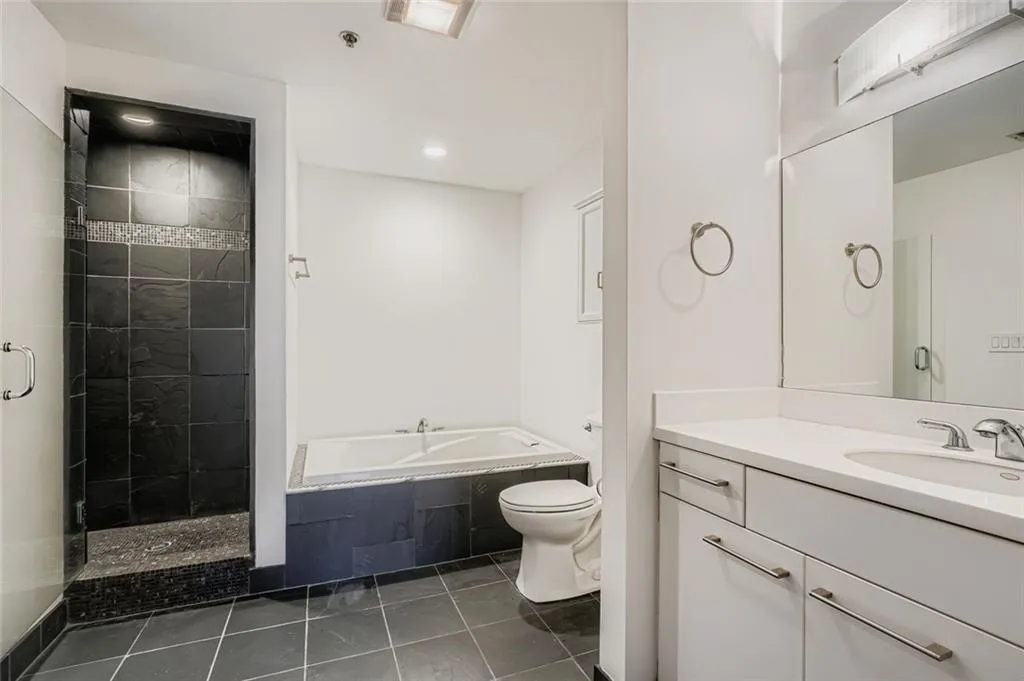 Bathroom featuring vanity, a garden tub, dark tile patterned flooring, a stall shower, and recessed lighting
