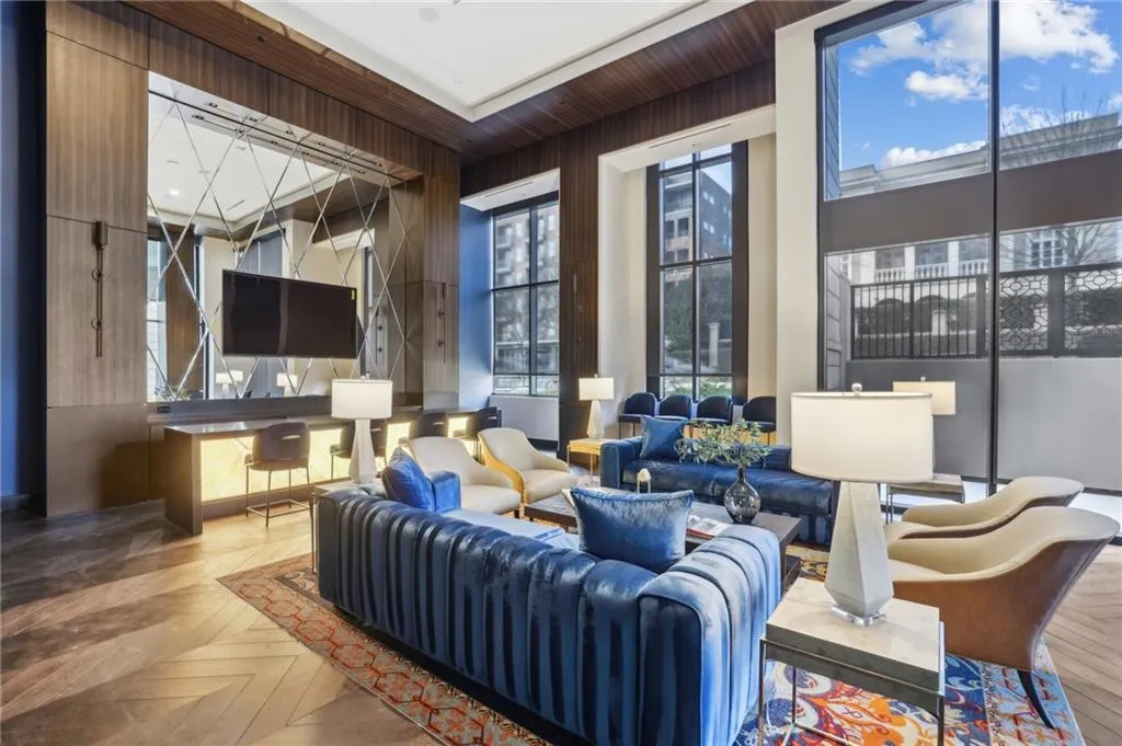 Herringbone wood-finish flooring, full-height windows, a built-in media console with mirrored accents, and wood paneling