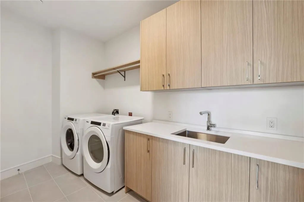 Utility area featuring light wood-finish cabinetry, white countertops, and a stainless steel sink