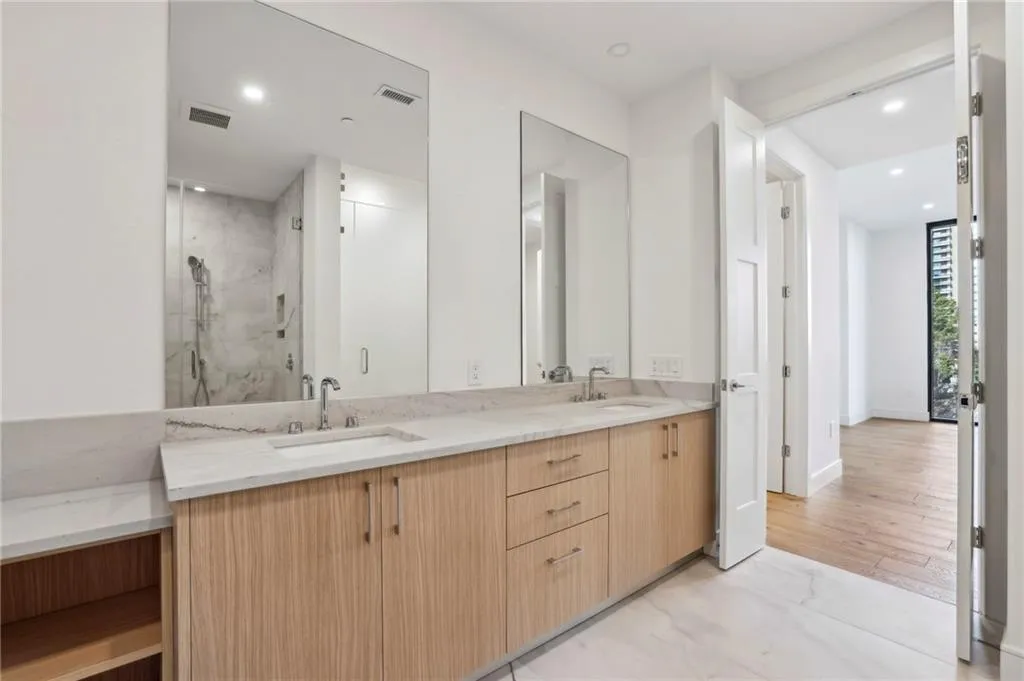 Dual vanity with undermount sinks, light wood-finish cabinetry, and a light-toned countertop