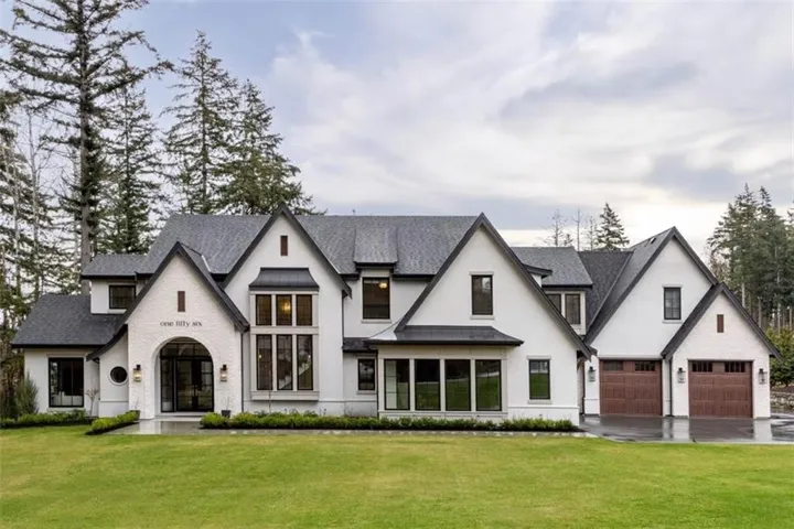 Modern Farmhouse estate featuring a striking white exterior with dark gray pitched rooflines and multiple gabled peaks