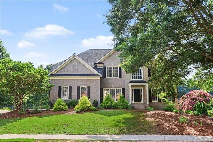 Traditional-style residence featuring a gray brick facade, dark roofing, and black shutters