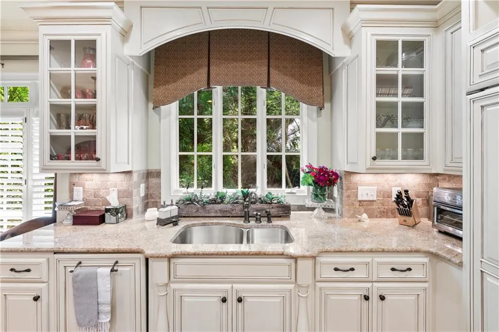 Kitchen featuring plenty of natural light, backsplash, and glass insert cabinets