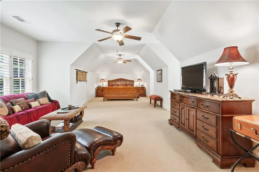 Bedroom with light colored carpet, vaulted ceiling, and a ceiling fan