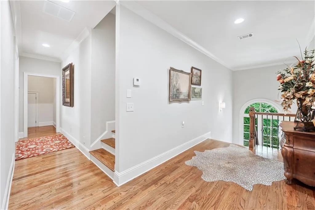 Corridor featuring light wood-type flooring, ornamental molding, and recessed lighting